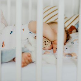 Baby sleeping with pacifier and stuffed toy in crib