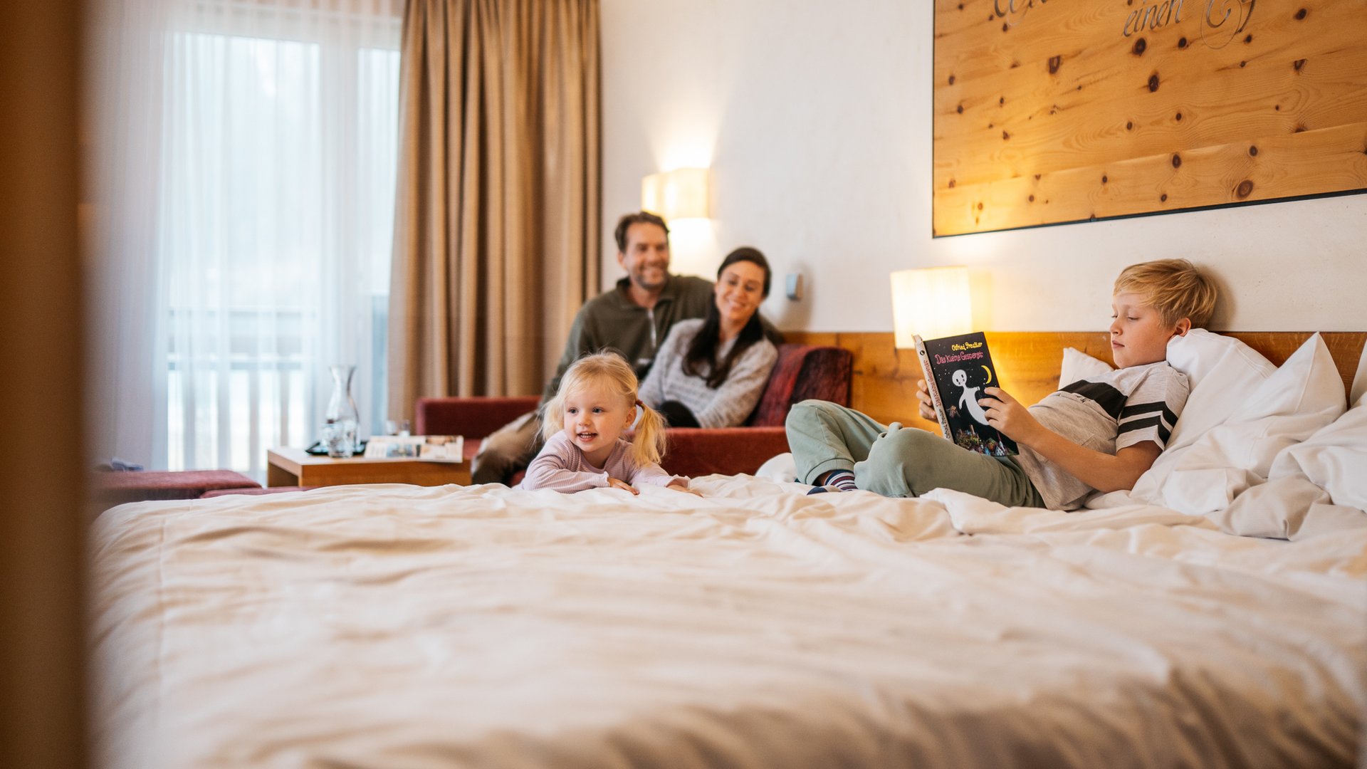 Familie mit zwei Kindern entspannt im Hotelzimmer