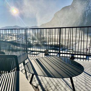 Balcony with chairs and table in snow, mountain view in sunlight