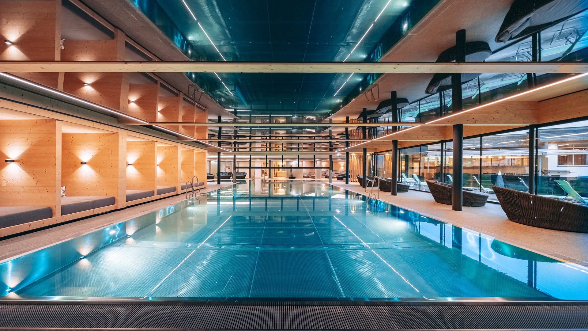 Modern indoor pool with wood paneling and lounge areas