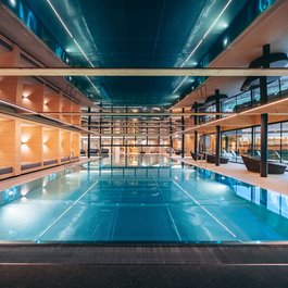 Modern indoor pool with wood paneling and lounge areas