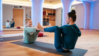Woman and boy doing yoga exercises together on mats in a room