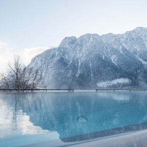Family wellness at Lake Achensee Infinity pool overlooking snow-covered mountains and winter landscape