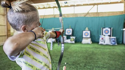 Child shooting a bow at targets indoors