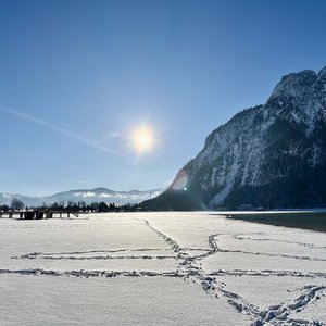 Family wellness at Lake Achensee Snowy landscape with mountain, sun, and footprints in the snow