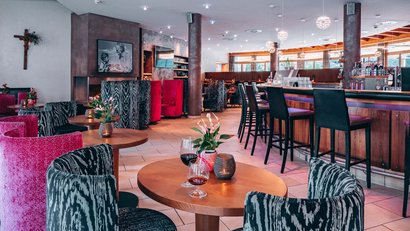 Modern café with wooden tables, colorful chairs, and bar area