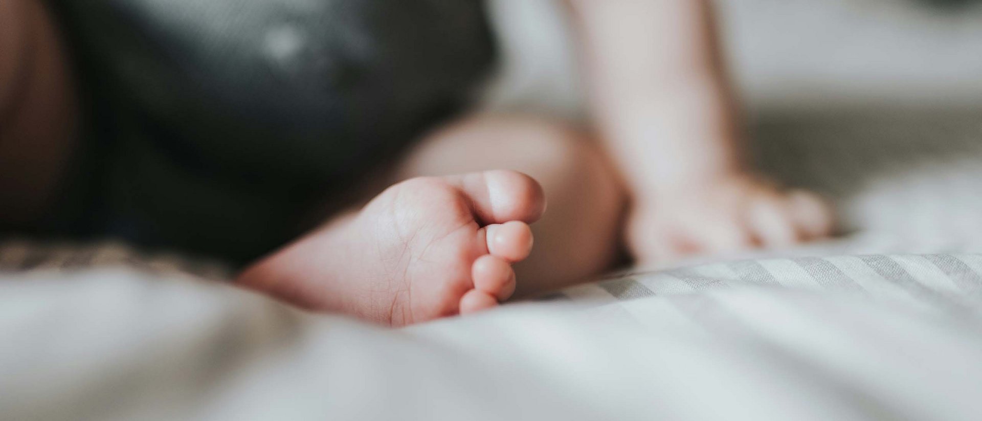 Pampering holidays with the little ones Close-up of baby foot and hand on a striped blanket